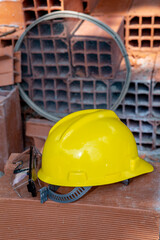 Yellow protective helmet and protective goggles  on pile of red bricks