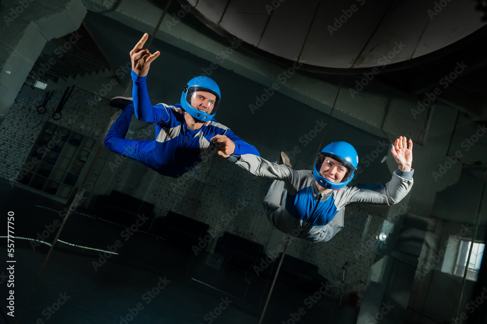 Wall mural A man and a woman enjoy flying together in a wind tunnel. Free fall simulator