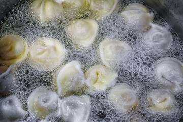 Dumplings with meat are boiled in boiling water, top view.