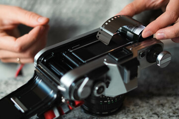 Girl's hands prepare an analog camera. Fingers of an expert photographer insert the film inside the camera. Vintage style, hipster culture and film cameras.