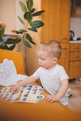 a child in a white T-shirt reads a book standing on the floor