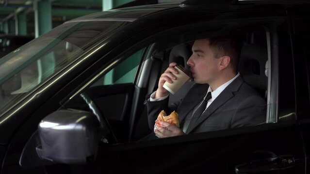 A young businessman is having lunch in a car