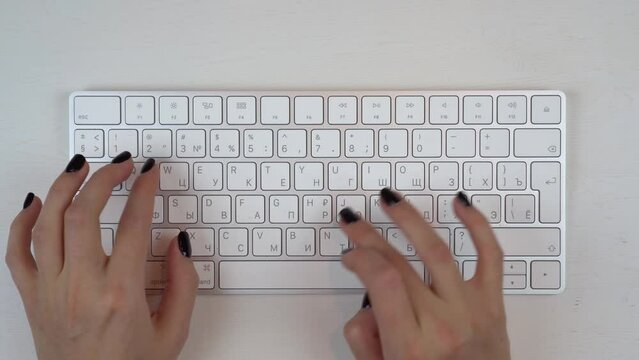 A young girl is typing on a wireless keyboard.