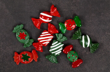 Festive sweets covered with colored icing sugar. In the form of Christmas red and green candies. Dark gray background. Top view