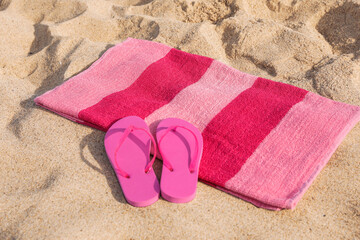 Fototapeta na wymiar Beach towel and stylish slippers on sand