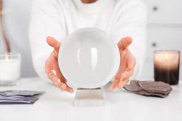 Soothsayer using crystal ball to predict future at table indoors, closeup