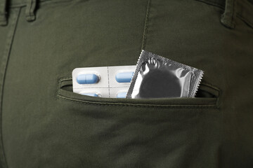 Jeans with pills and condom in pocket, closeup. Potency problem