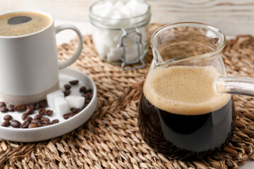 Turkish coffee. Glass cezve and cup with hot aromatic coffee and sugar on wicker mat