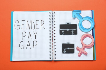 Gender pay gap. Notebook, paper briefcases with male and female symbols on orange background, top view