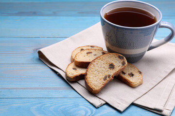 Sweet hard chuck crackers with raisins and cup of tea on light blue wooden table. Space for text