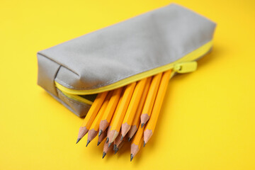 Many sharp pencils in pencil case on yellow background