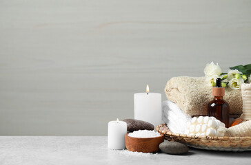 Beautiful composition with burning candles and different spa products on light grey table. Space...