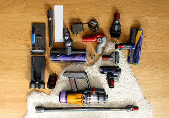Knolling style above modern wireless Vacuum Cleaner powerful cordless colorful cyclonic dust collection - all accessories on the wooden parquet floor with Irish sheepskin rug
