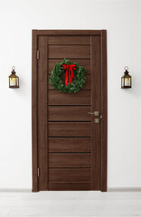 Beautiful Christmas wreath with red bow hanging on door