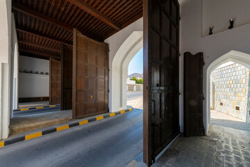 The large, carved wooden doors and arched gates under the Omani Gate Museum in the Arabic city of Muscat, Oman.