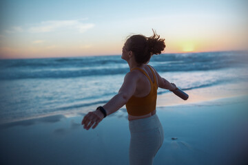 relaxed active sports woman rejoicing at beach at sunset