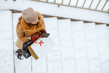 woman in brown hat and scarf using phone applications