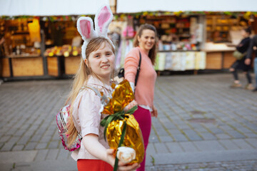 smiling mother and teenage daughter walking at fair in city