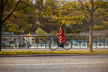 Fototapeta woman in red rain coat outdoors on city street riding bicycle obraz