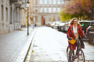 smiling elegant woman outside on city street riding bicycle