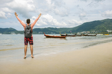 Happy man arms outstretched by the sea enjoying freedom and life, people travel vacation holiday concept