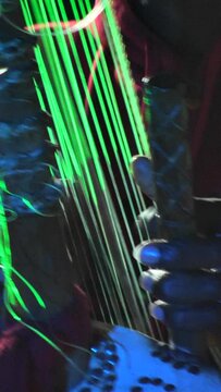 Vertical video of Black man dancing while his fingers are plucking the strings of kora instrument