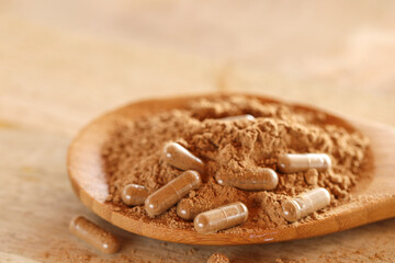 Guarana capsules in powder in a wooden spoon on a wooden table.Supplements and vitamins. Healthy...