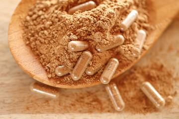 Transparent capsules with guarana powder.Alternative medicine . Guarana capsules in guarana powder in a wooden spoon on a wooden table.Supplements and vitamins. Healthy eating. sports nutrition.
