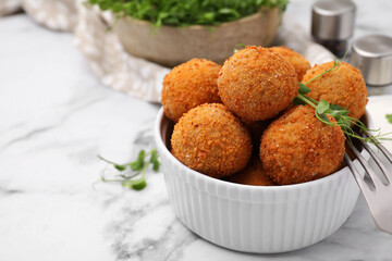 Bowl of delicious fried tofu balls with pea sprouts on white marble table, space for text