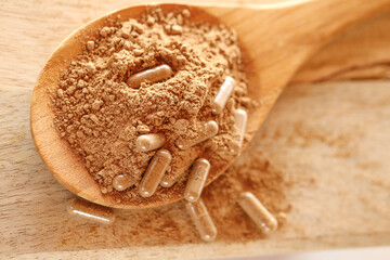 Guarana capsules in guarana powder in a wooden spoon on a wooden table.Supplements and vitamins....