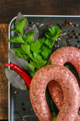  sausage rings , fresh parsley, red chili peppers in a black dish on a dark wooden table.Delicious...