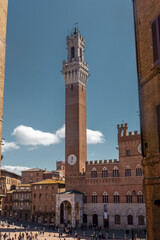 Fototapeta premium Tourists enjoy Piazza del Campo square in Siena, Italy. The historic centre of Siena has been declared by UNESCO a World Heritage Site.
