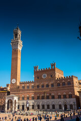 Fototapeta premium Tourists enjoy Piazza del Campo square in Siena, Italy. The historic centre of Siena has been declared by UNESCO a World Heritage Site.