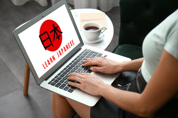 Young woman with laptop studying Japanese at home