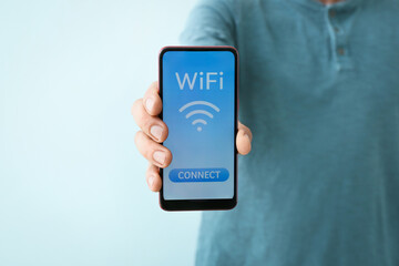 Man holding mobile phone with WiFi symbol and connection button on color background