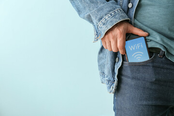 Man putting mobile phone with WiFi symbol into pocket, closeup