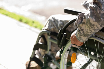 Young soldier in wheelchair outdoors, closeup