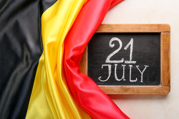 Belgian flag and board with text 21 JULY on light background, closeup