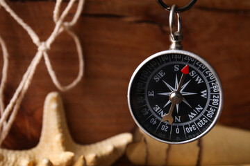 Compass hanging on wooden background, closeup