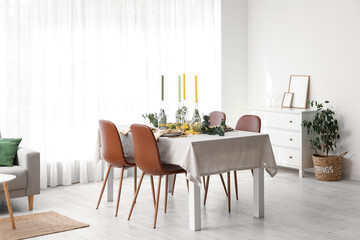 Table with festive setting and floral decor in light room interior