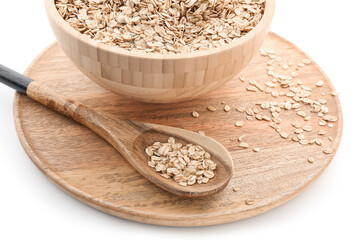 Wooden board with bowl and spoon of raw oatmeal on white background, closeup