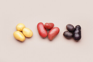 Heaps of different raw potatoes on color background