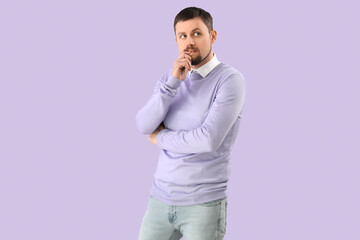 Handsome man biting nails on lilac background