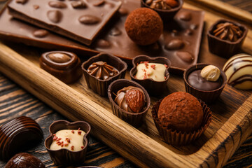 Board with chocolate bars and candies on wooden background