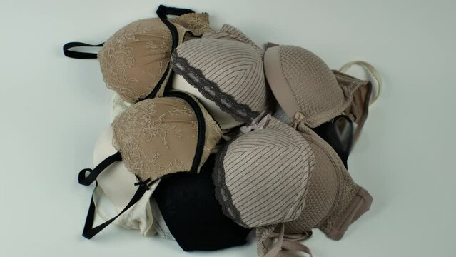 Close-up of a female bras piled up in a heap on a light background. Colorful erotic women's bras. Women's underwear. The concept of women's wardrobe. Flat lay