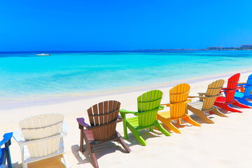 Colorful wooden chairs on white sand beach in Aruba, Duth Caribbean