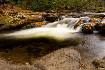 Long exposure waterfall in Smoky Mountain National Park during fall autumn with colorful leaves and silky smooth water. Cades Cove Tennessee