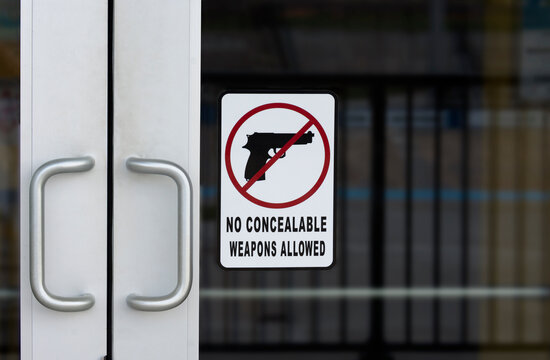 NO CONCEALABLE WEAPONS ALLOWED sign on the outside of a door on public building warning people not bring their guns inside.