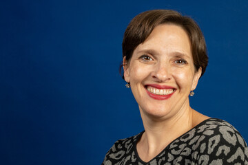 Brunette woman in fashionable print top on blue background.