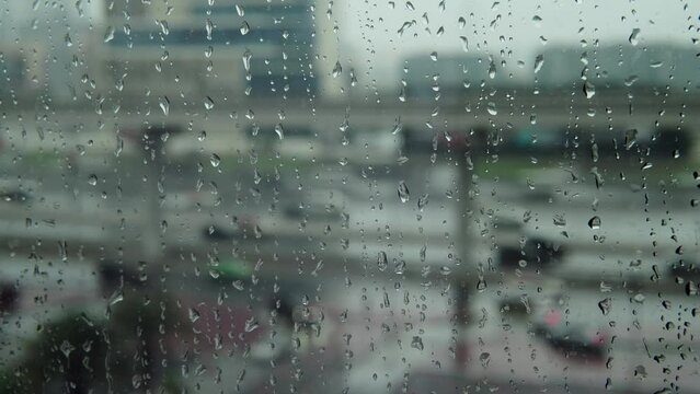 Window rain. Raindrops on the window. Its raining outside. Close-up shot. View from the window to the road with passing cars. 